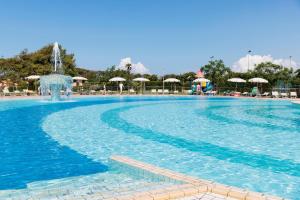 a swimming pool with a fountain and chairs and umbrellas at Gitavillage California in Montalto di Castro +37 photos