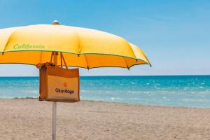 a yellow umbrella on the beach with a shopping bag at Gitavillage California in Montalto di Castro