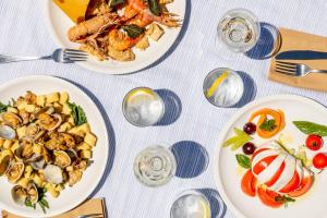 a table with plates of food and glasses of wine at Gitavillage California in Montalto di Castro