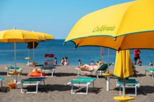 a beach with chairs and umbrellas and people on the beach at Gitavillage California in Montalto di Castro