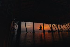 une personne debout sur la plage au coucher du soleil dans l'établissement Cocobay Resort Kumarakom, à Kumarakom