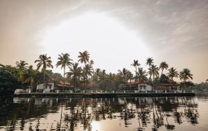 a body of water with palm trees and houses at Cocobay Resort Kumarakom in Kumarakom