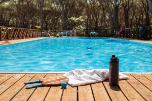 a towel and a thermos next to a swimming pool at Gitavillage Le Marze in Marina di Grosseto