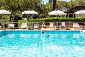 a dog standing in the water in a swimming pool at Argentario Osa Resort in Talamone