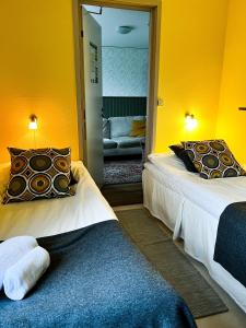 two beds in a room with yellow walls at Svabesholms Kungsgårds B&B och Pensionat Stenshuvud in Kivik