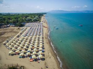 eine Luftansicht auf einen Strand mit Sonnenschirmen und dem Meer in der Unterkunft Argentario Osa Resort in Talamone