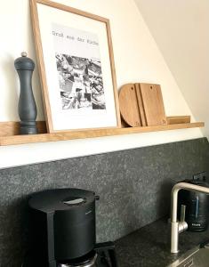 une photo sur une étagère au-dessus d'un évier et d'une cafetière dans l'établissement Harzpur Lodge - Pure Entspannung in purer Natur, à Hahnenklee