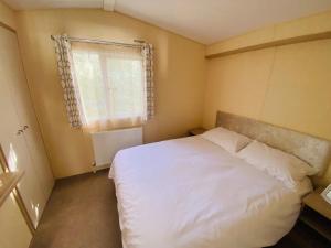 a small bedroom with a white bed and a window at New Forest Bees Holiday Home, Bashley in New Milton