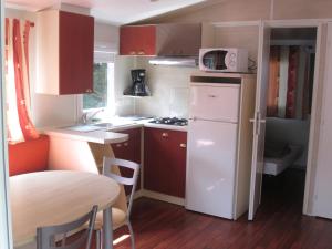 a small kitchen with a white refrigerator and a table at Camping de masevaux in Masevaux
