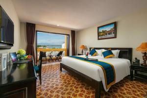 ホイアンにあるLa Charm Hoi An Hotel & Spaの大きなベッドとバルコニーが備わるホテルルームです。