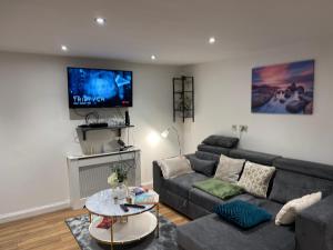 a living room with a couch and a tv at Central Cheltenham Apartment in Cheltenham