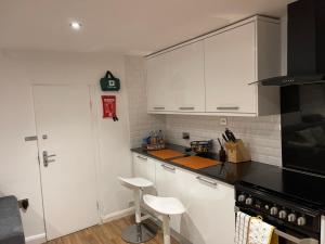 a kitchen with white cabinets and a black counter top at Central Cheltenham Apartment in Cheltenham