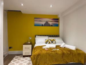 a bedroom with a bed with a yellow wall at Central Cheltenham Apartment in Cheltenham