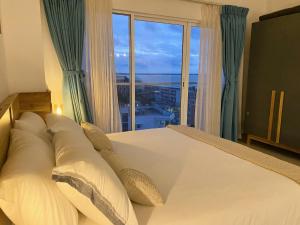 a bedroom with a white bed with a large window at Beachside Studio Retreat in Negombo