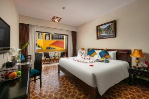 a hotel room with a large bed and a television at La Charm Hoi An Hotel - Peaceful Boutique In Old Town in Hoi An