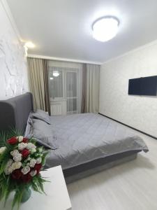 ein Schlafzimmer mit einem Bett und einem Tisch mit Blumen in der Unterkunft Трёхкомнатная квартира ВИП in Kökschetau