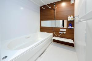 a bathroom with a white tub and wooden walls at Pacific Coast Enoshima by Tranova in Fujisawa