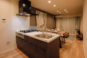 a kitchen with a sink and a stove and a table at Pacific Coast Enoshima by Tranova in Fujisawa