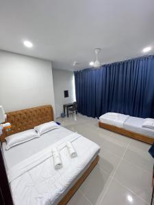 a bedroom with two beds and a blue curtain at TAMU ROOMSTAY TOK MOLOR in Kuala Terengganu