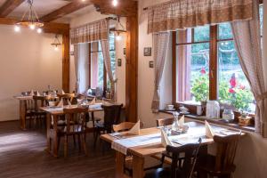 ein Restaurant mit Holztischen, Stühlen und Fenstern in der Unterkunft Hospůdka pod Rablinů in Kašava