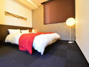 um quarto com uma cama grande e um cobertor vermelho em The Garden Place Hiroshima - Vacation STAY 89703v em Hiroshima