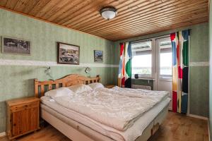 1 dormitorio con cama y techo de madera en Cottage with its own sandy beach near Vimmerby, en Vimmerby
