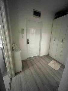 una stanza vuota con una porta bianca e pavimenti in legno di Orlando apartman a Kotor (Cattaro)