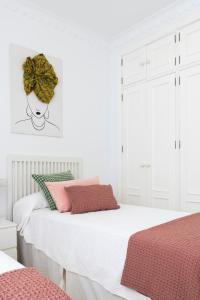 een slaapkamer met 2 bedden en een krans aan de muur bij Magno Apartments Alfarería - Private Parking included in Sevilla