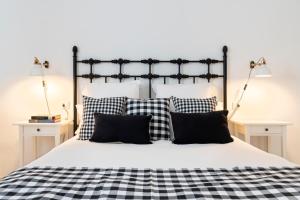 een slaapkamer met een zwart-wit bed met kussens bij Magno Apartments Alfarería - Private Parking included in Sevilla