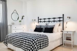 een witte slaapkamer met een zwart-wit bed en een spiegel bij Magno Apartments Alfarería - Private Parking included in Sevilla