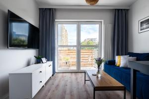 een woonkamer met een blauwe bank en een groot raam bij Apartament PRIMAVERA z miejscem parkingowym in Toruń
