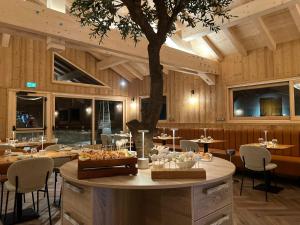 a restaurant with tables and a tree in the middle at Hôtel Saint-Martin in Saint-Martin-de-Belleville