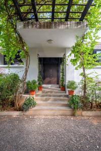 eine Treppe, die zu einem Gebäude mit Topfpflanzen führt in der Unterkunft LohonoStays Villa Amber in Alibag