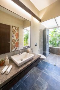 ein Badezimmer mit einem Waschbecken, einer Badewanne und einem Spiegel in der Unterkunft LohonoStays Villa Amber in Alibag