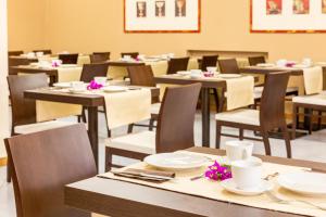 a dining room with tables and chairs with flowers on them at Park Hotel Residence in Orbetello +63 photos