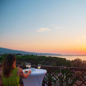 een vrouw aan een tafel met een glas wijn bij Park Hotel Residence in Orbetello