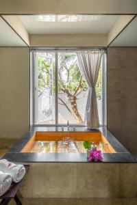 eine Badewanne in einem Zimmer mit Fenster in der Unterkunft LohonoStays Villa Amber in Alibag