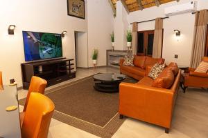 Il comprend un salon doté d'un mobilier orange et d'une télévision à écran plat. dans l'établissement Kruger Park Lodge Unit 268 - PMP, à Hazyview