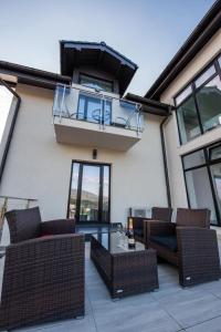 a patio with wicker furniture and a balcony at Pensiunea Carul cu flori in Oraviţa