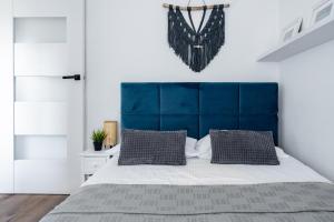 een slaapkamer met een groot bed met een blauw hoofdeinde bij Apartament PRIMAVERA z miejscem parkingowym in Toruń