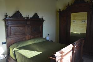 sypialnia z dużym drewnianym łóżkiem z zieloną pościelą w obiekcie Ca'Os Locanda&Grill w mieście Vigostano