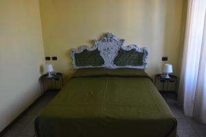 sypialnia z zielonym łóżkiem i 2 stolikami bocznymi w obiekcie Ca'Os Locanda&Grill w mieście Vigostano