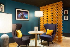 a room with two chairs and a table with a lamp at Hotel Les Capitouls Toulouse Centre - Handwritten Collection in Toulouse