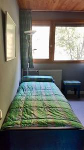 a bedroom with a bed with a colorful comforter and a window at L'Ariondaz - Appartement au centre du village, proche des pistes, avec parking in Courchevel