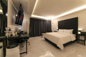 天安市Aden Hotel的卧室里有一张白色的大床和一台电视