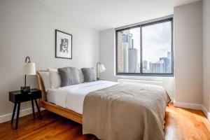 een witte slaapkamer met een bed en een groot raam bij Midtown 2br w elevator wd nr entertainment NYC-1227 in New York