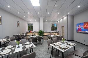 a dining room with tables and chairs and a screen at Vizhanwan Hotel Shenzhen International Convention and Exhibition Center in Shenzhen