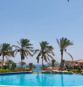 una piscina con palmeras y el océano en el fondo en Private Waterfront Villa, en Ain Sokhna