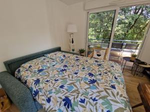 a bedroom with a bed with a blue and white comforter at Appartement Spacieux avec Parking proche MER in Saint-Nazaire