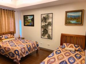 two beds in a room with paintings on the wall at A nature’s den in Tagaytay in Tagaytay +15 photos